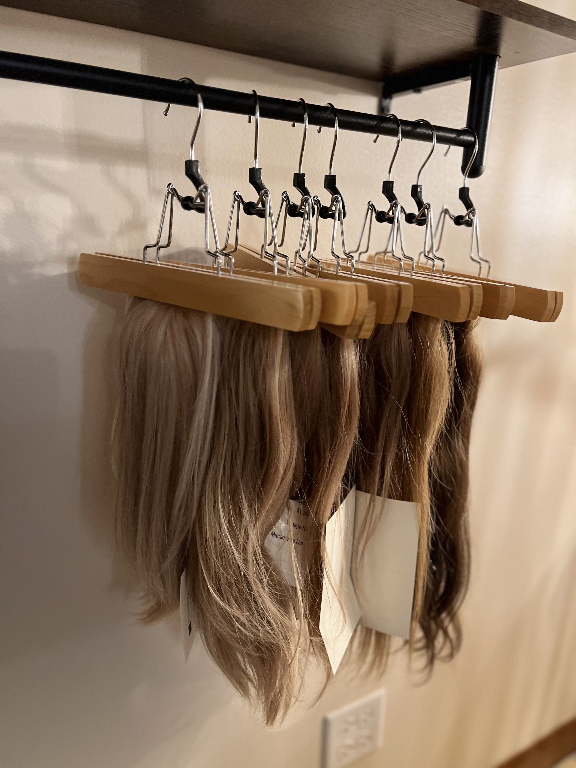 A bunch of wigs are hanging on a wooden rack — St. Charles, IL — Studio Genesis - Hair Loss Solutions