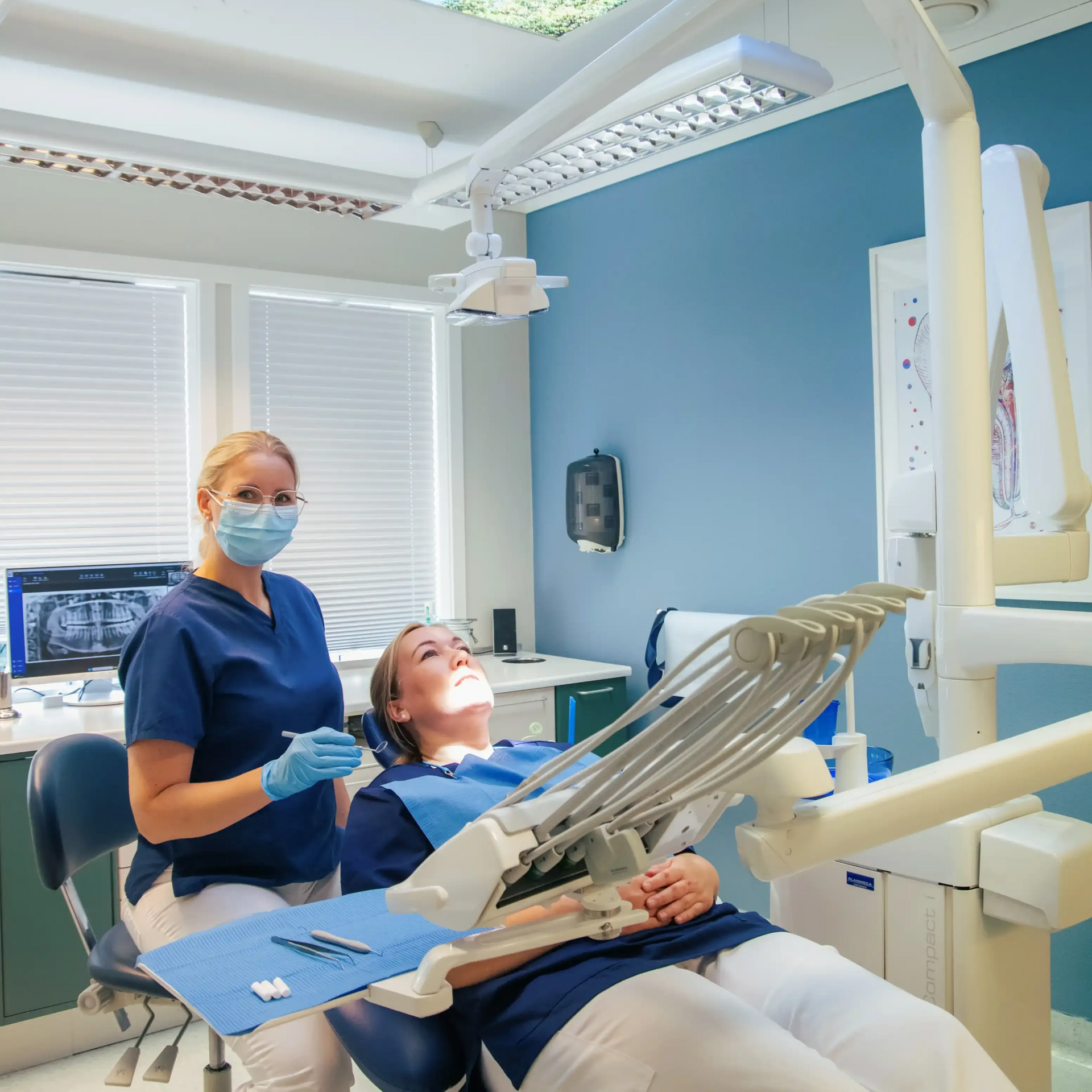 Seks kvinner i skrubber smiler i lyse omgivelser innendørs.