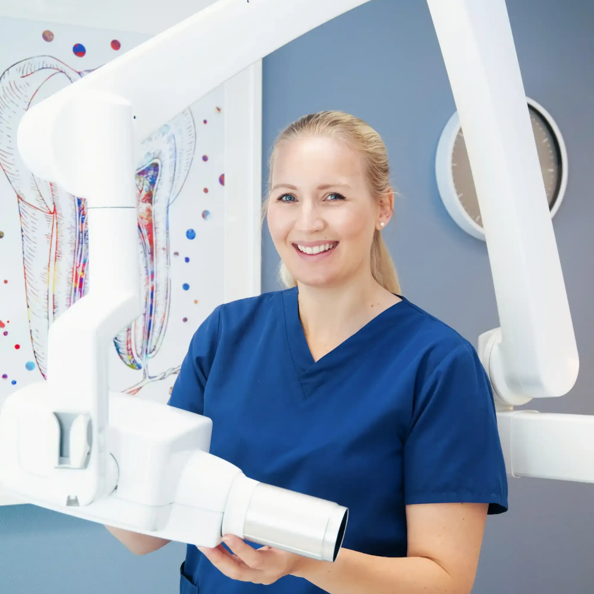 Tannlege Christian med briller og skjegg, iført blå skjorte og medisinsk maske, smiler til kameraet.