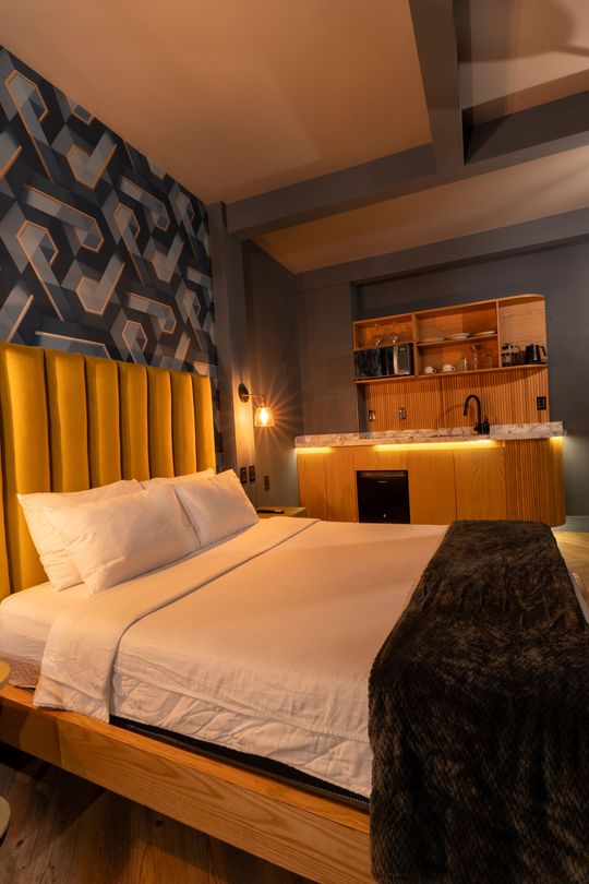 A hotel room with a king size bed and a kitchen.