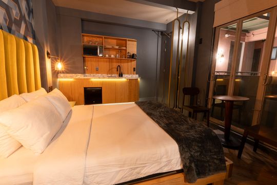 A hotel room with a bed , table , chairs and a kitchen.