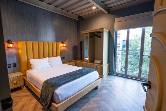 A hotel room with a king size bed and a large window.