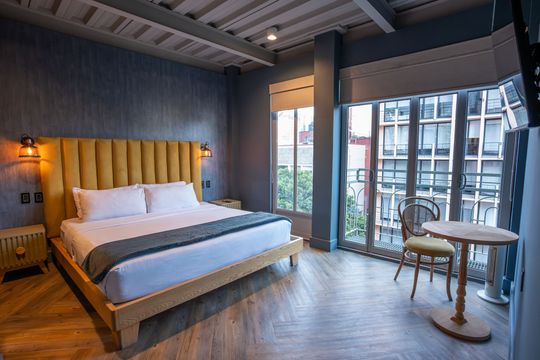 A hotel room with a king size bed , table and chairs.