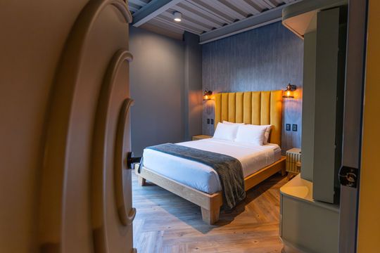 A hotel room with a bed and a door leading to it.