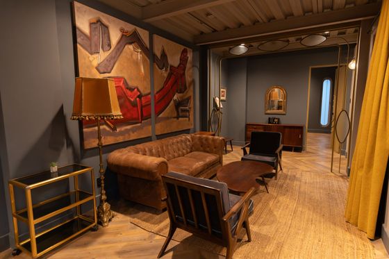 A living room with a couch , chairs , tables and a painting on the wall.