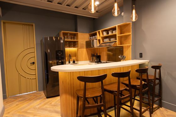 A kitchen with a bar and stools and a refrigerator.