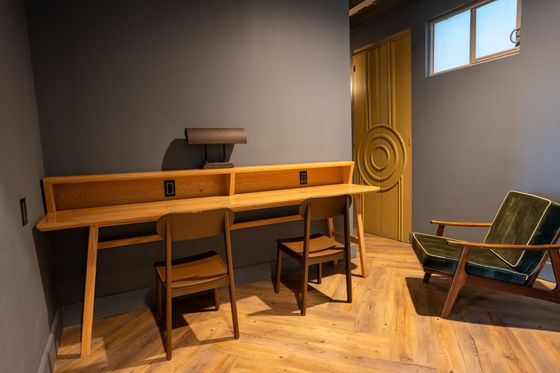A room with a desk and chairs in it.