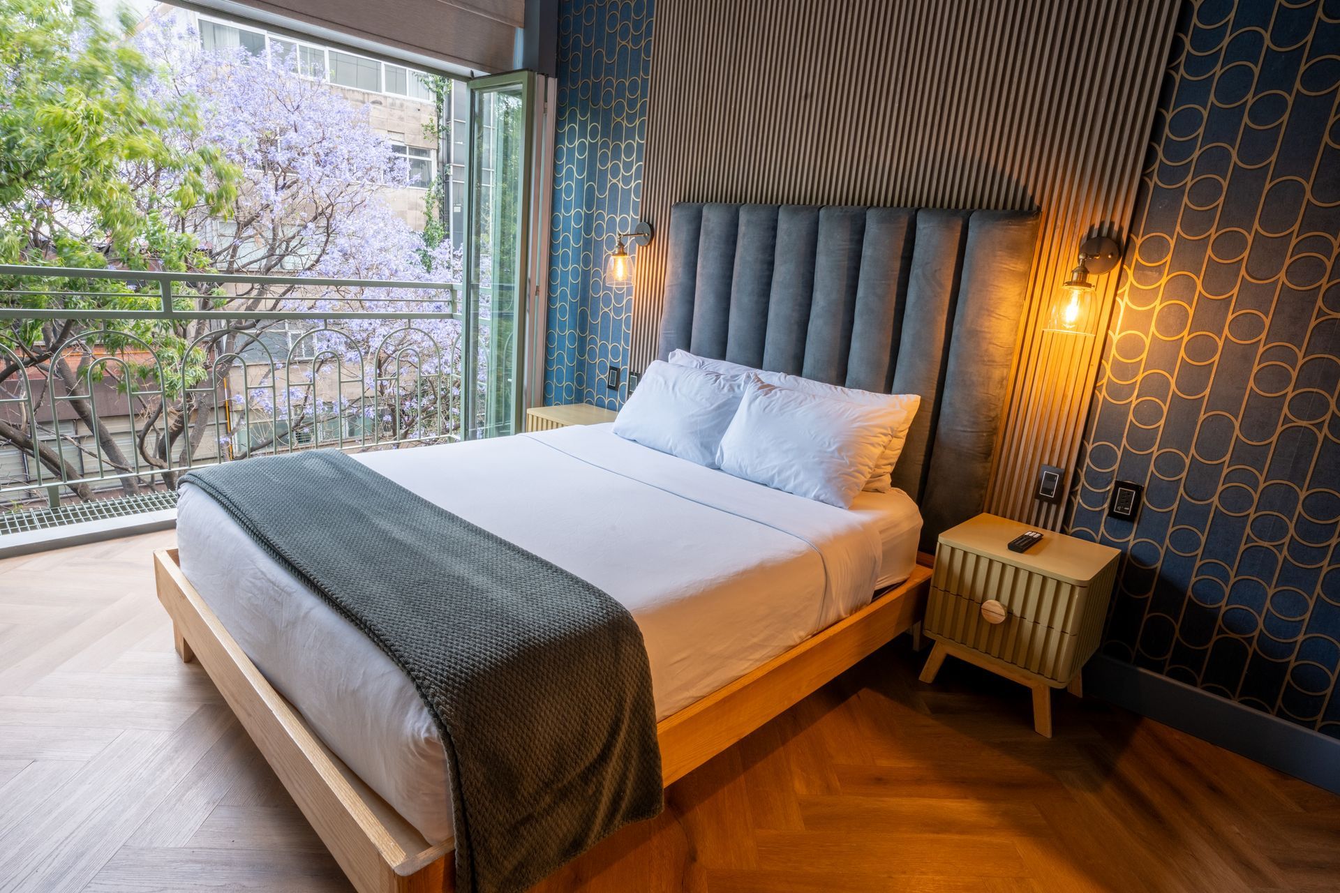 A hotel room with a bed , nightstand , and balcony.
