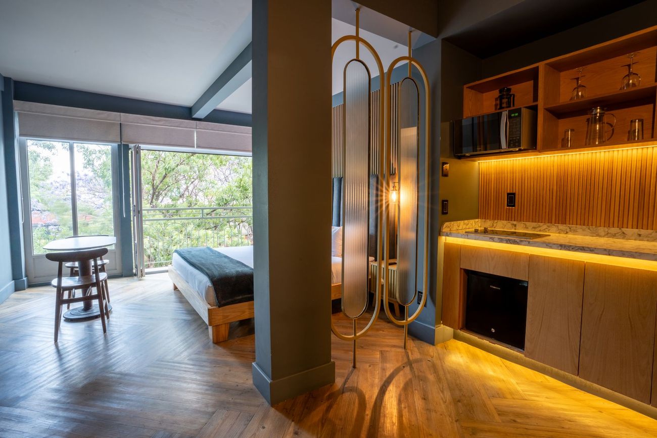 A hotel room with a bed , table , and mirror.