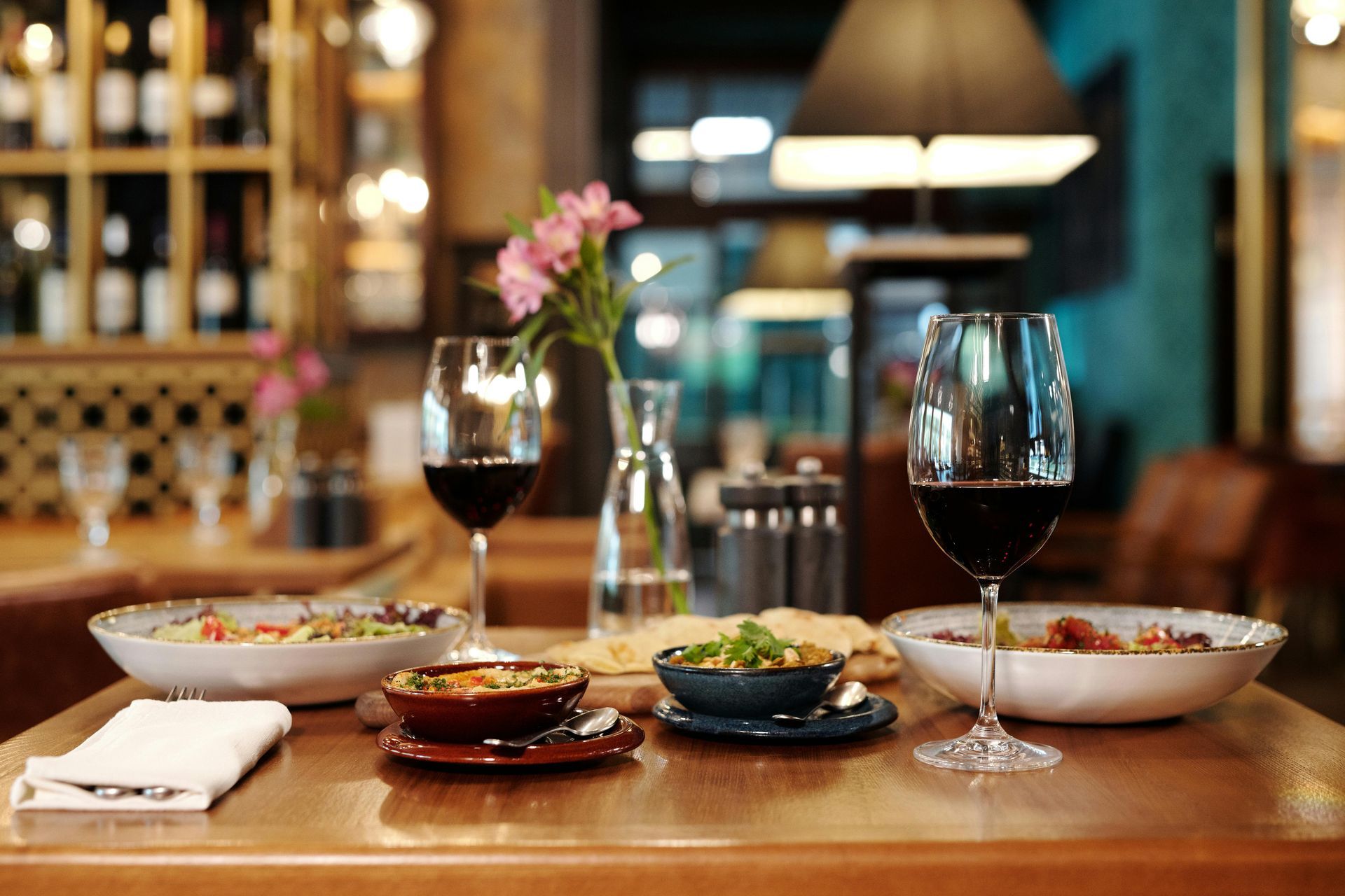 A table with plates of food and wine glasses on it in a restaurant.