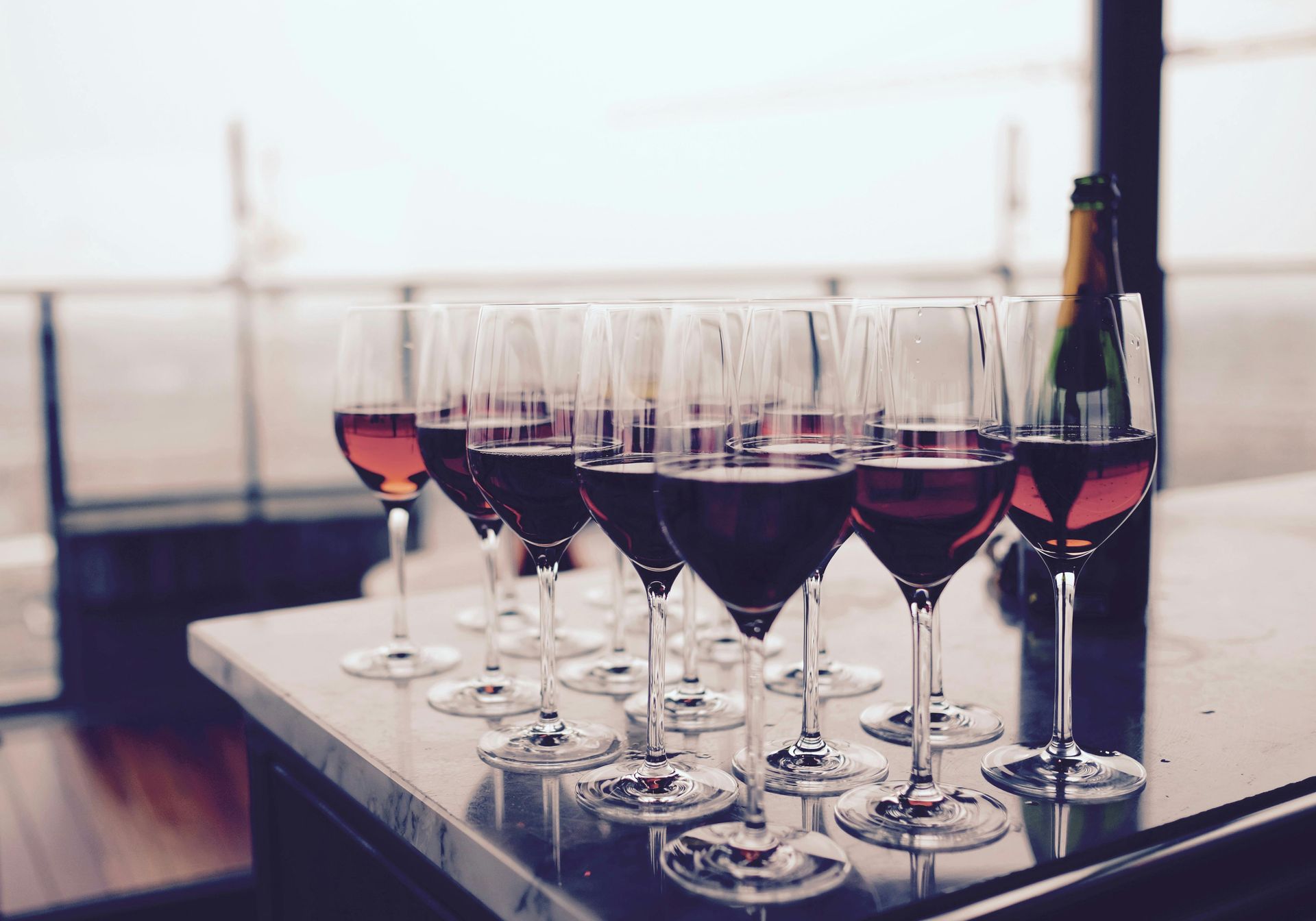 A row of wine glasses are lined up on a table.