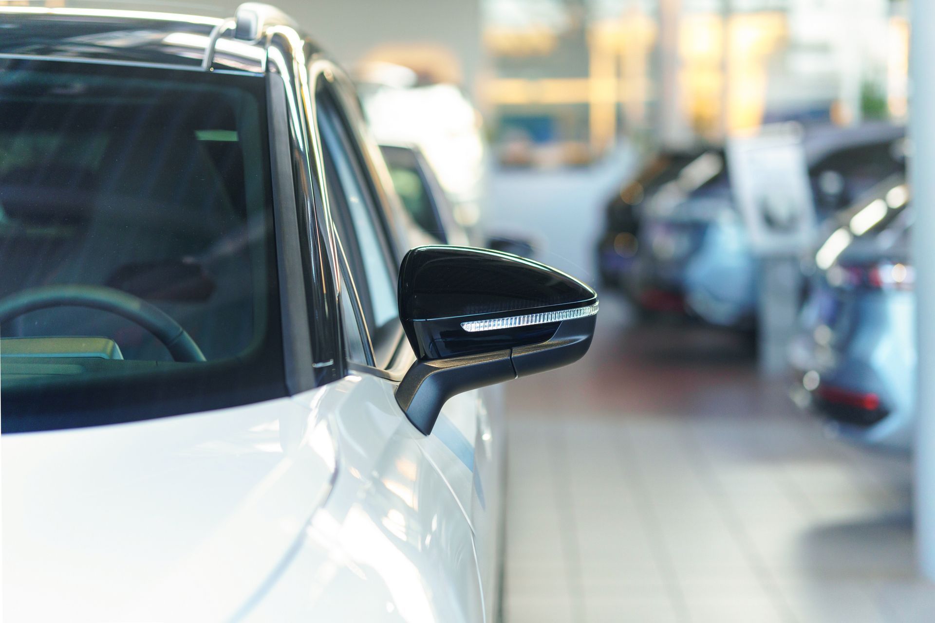 Un'auto bianca è parcheggiata in uno showroom insieme ad altre auto.