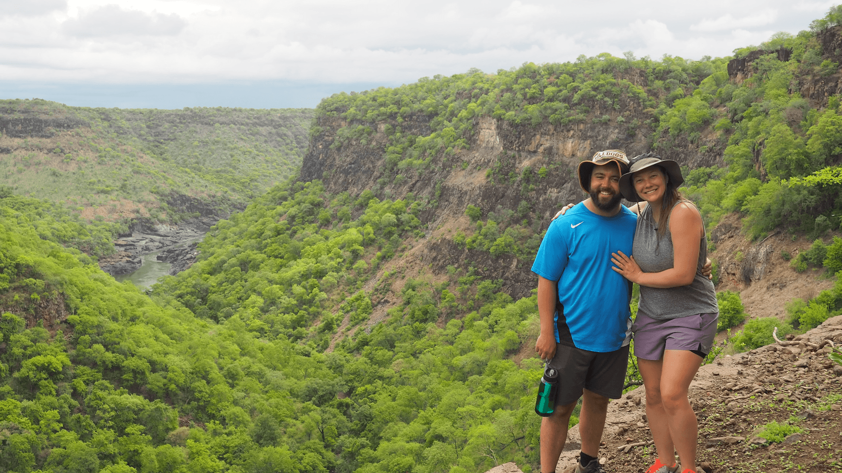 A man and a woman are posing for a picture on top of a mountain.