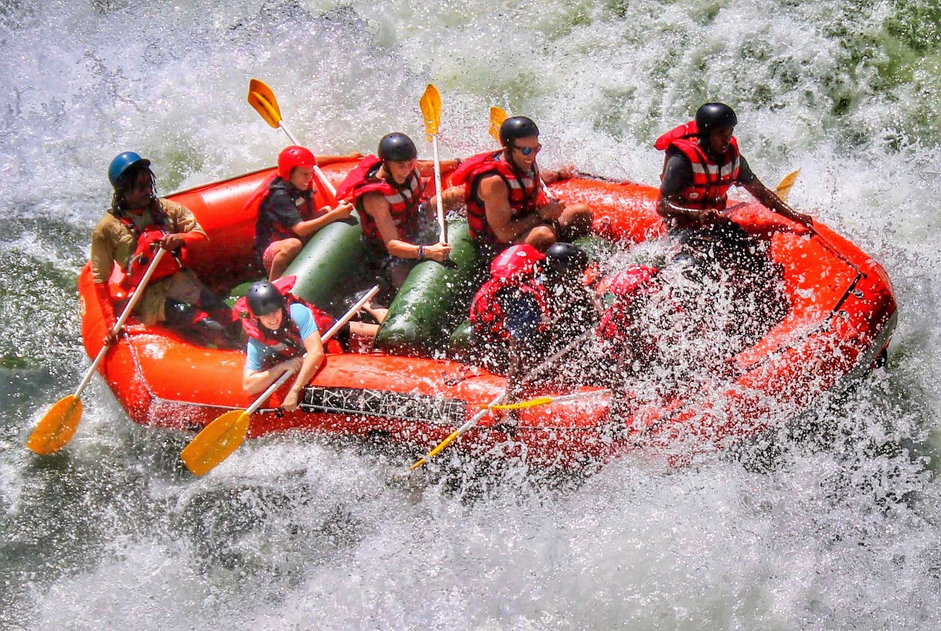 A group of people are rafting down a river in an orange raft.