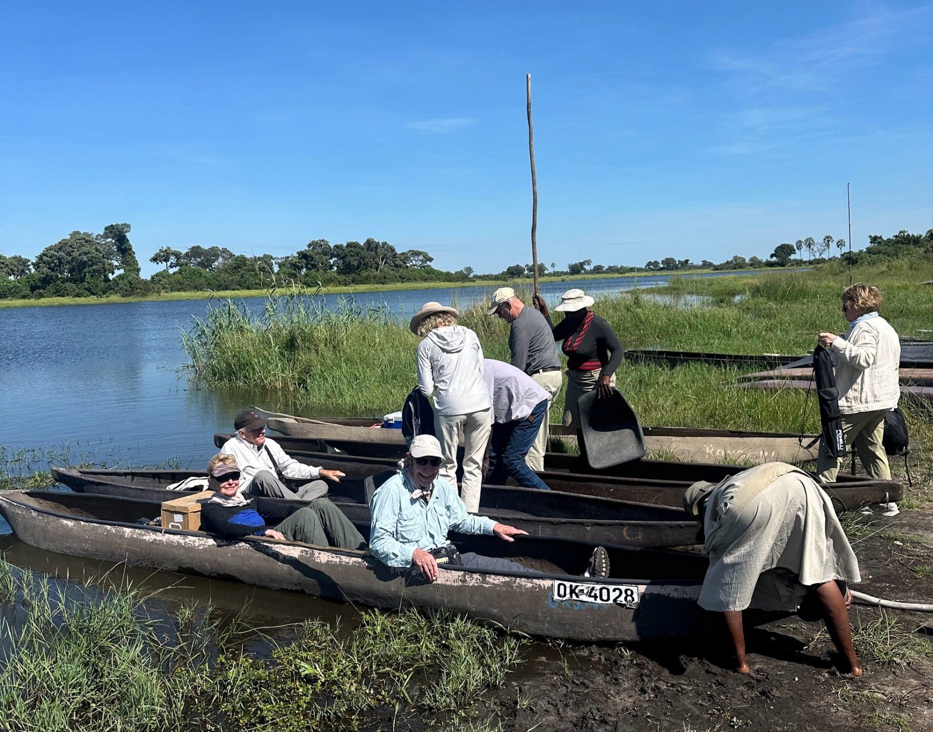 A group of people are sitting in boats on the shore of a lake