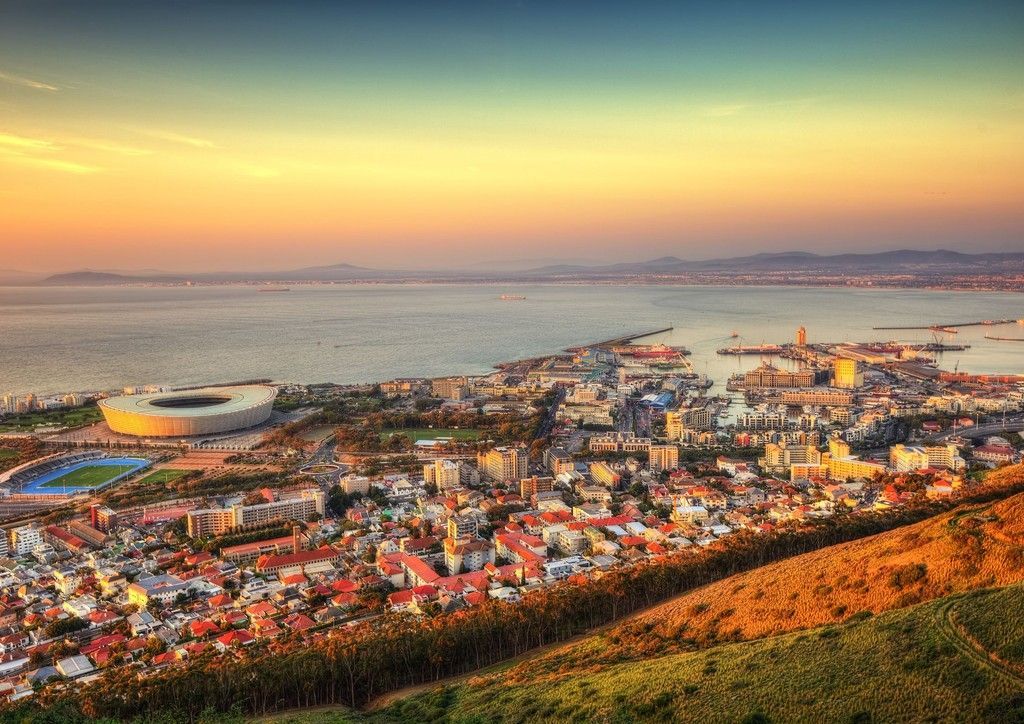 An aerial view of a city next to a body of water at sunset.