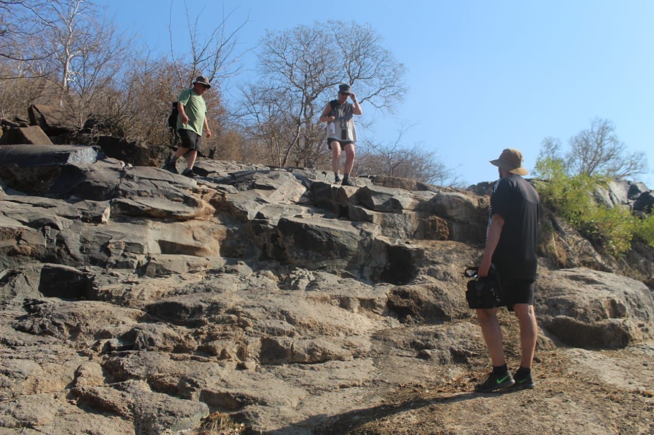 A group of people are standing on top of a rocky hill.