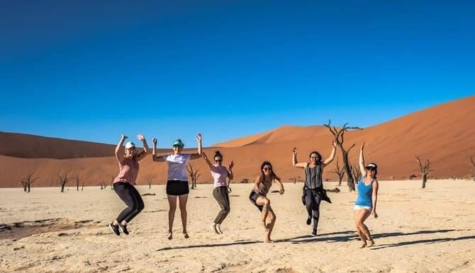 A group of women are jumping in the air in the desert.