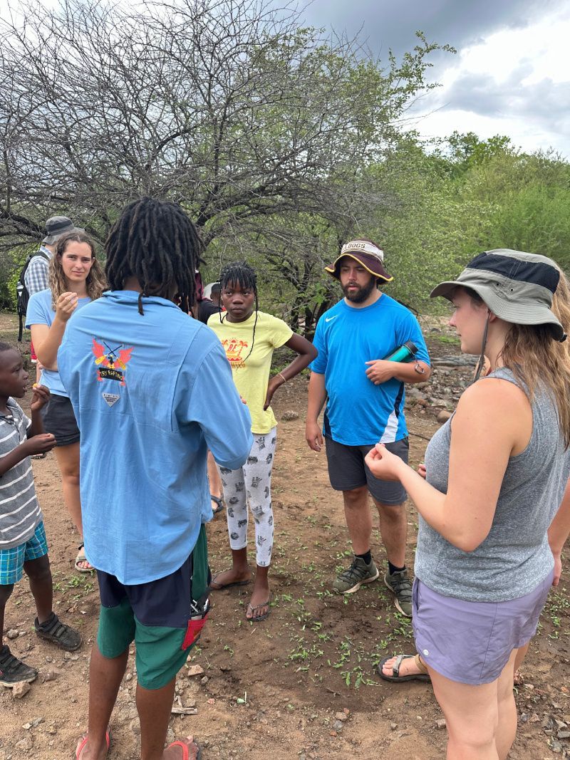 Group of people, mostly in casual wear, gathered outdoors, possibly for an activity or discussion.
