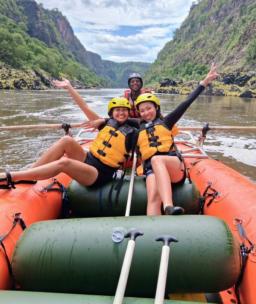 Two women are sitting in a raft on a river.