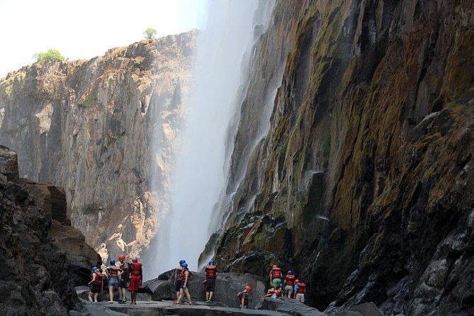 A group of people are standing in front of a waterfall.