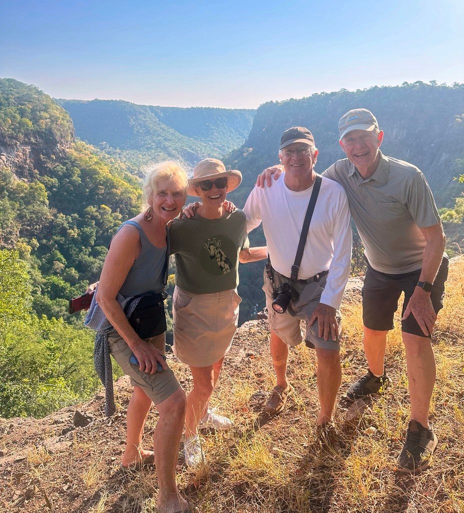 A group of people are posing for a picture on top of a mountain.