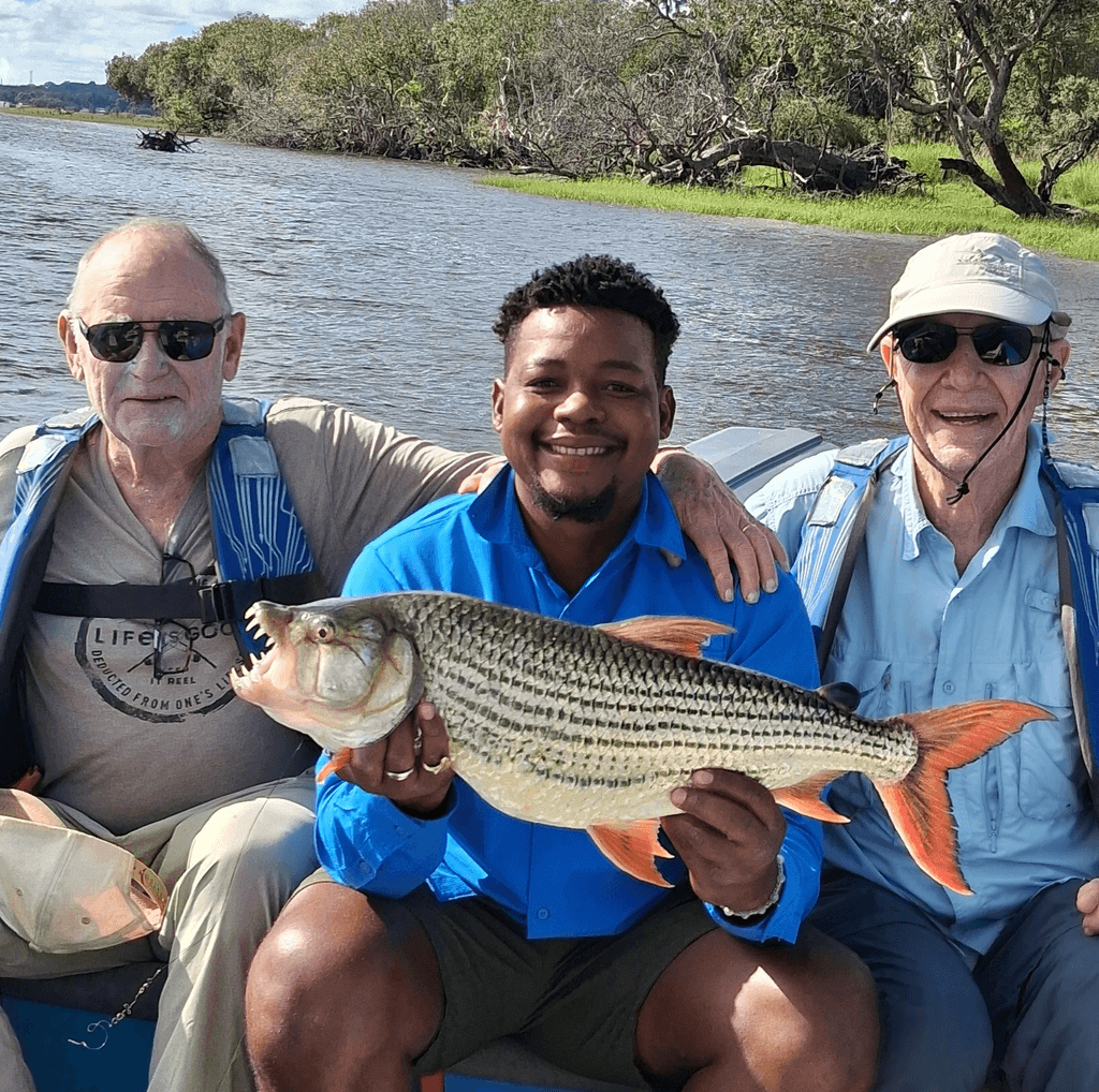 Three men are sitting on a boat holding a large fish.