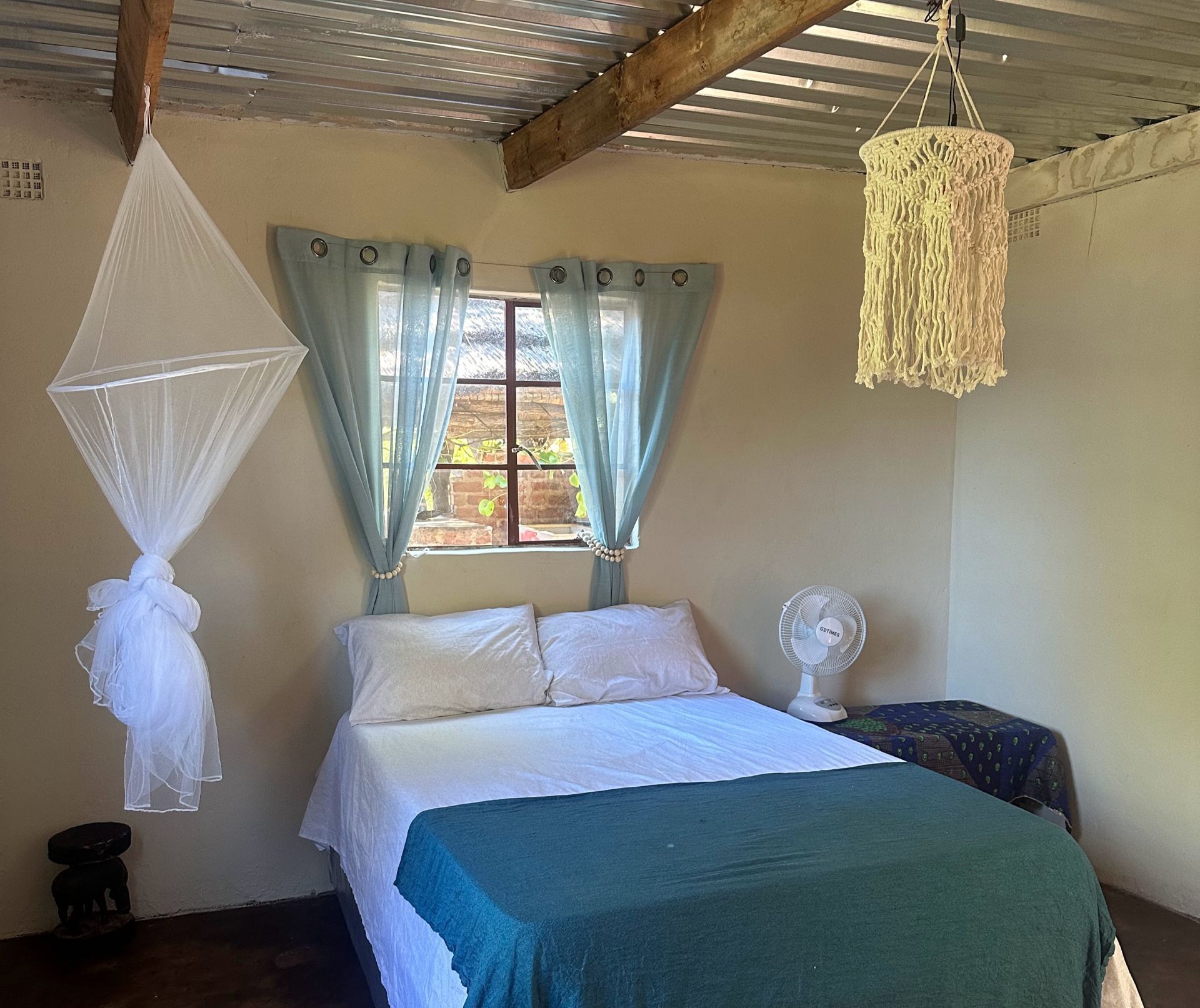 A bedroom with a bed , mosquito nets and a fan