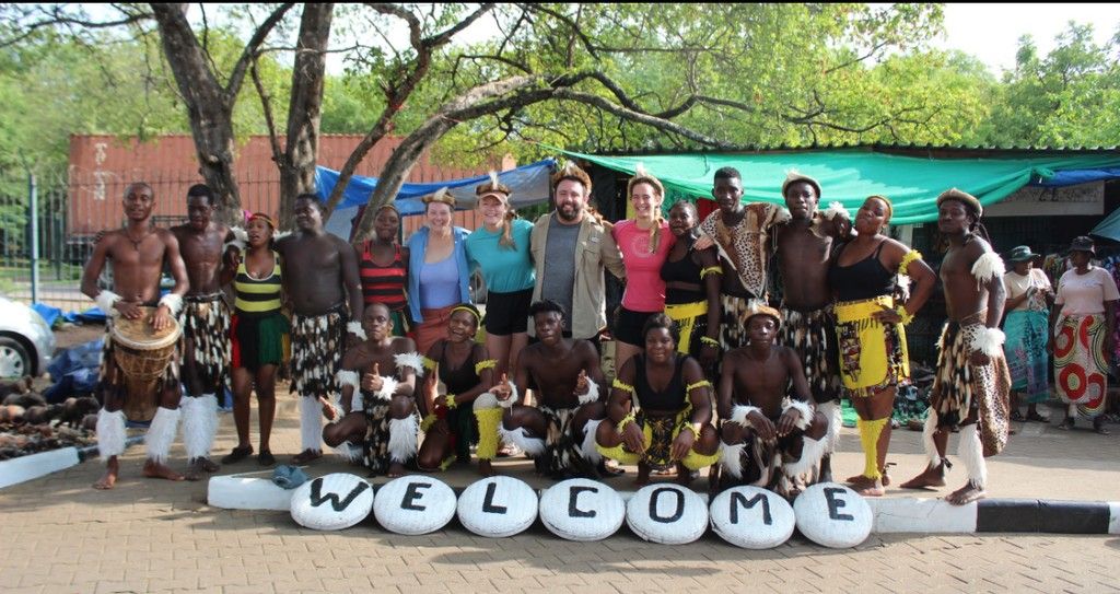 A group of people standing in front of a sign that says welcome