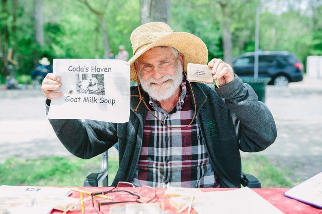 A man in a straw hat is sitting at a table holding a sign.