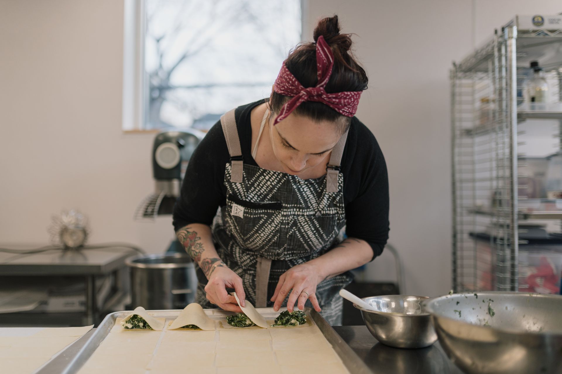 A woman is cutting vegetables on a cutting board in a kitchen.