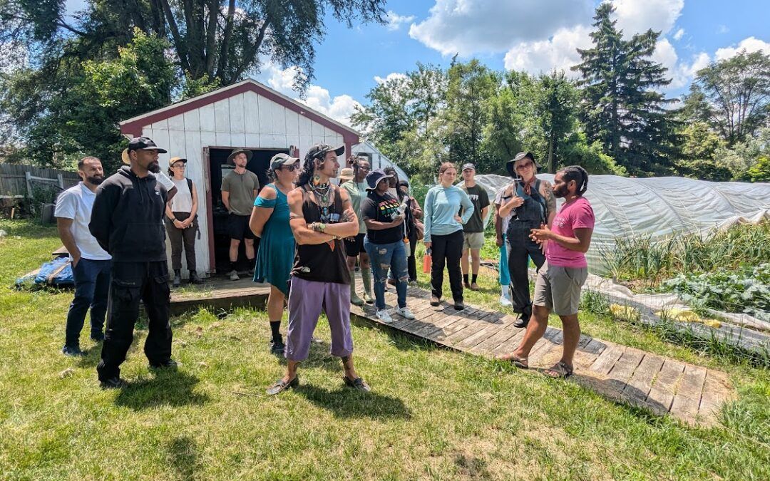 A group of people are standing in a grassy field in front of a shed.