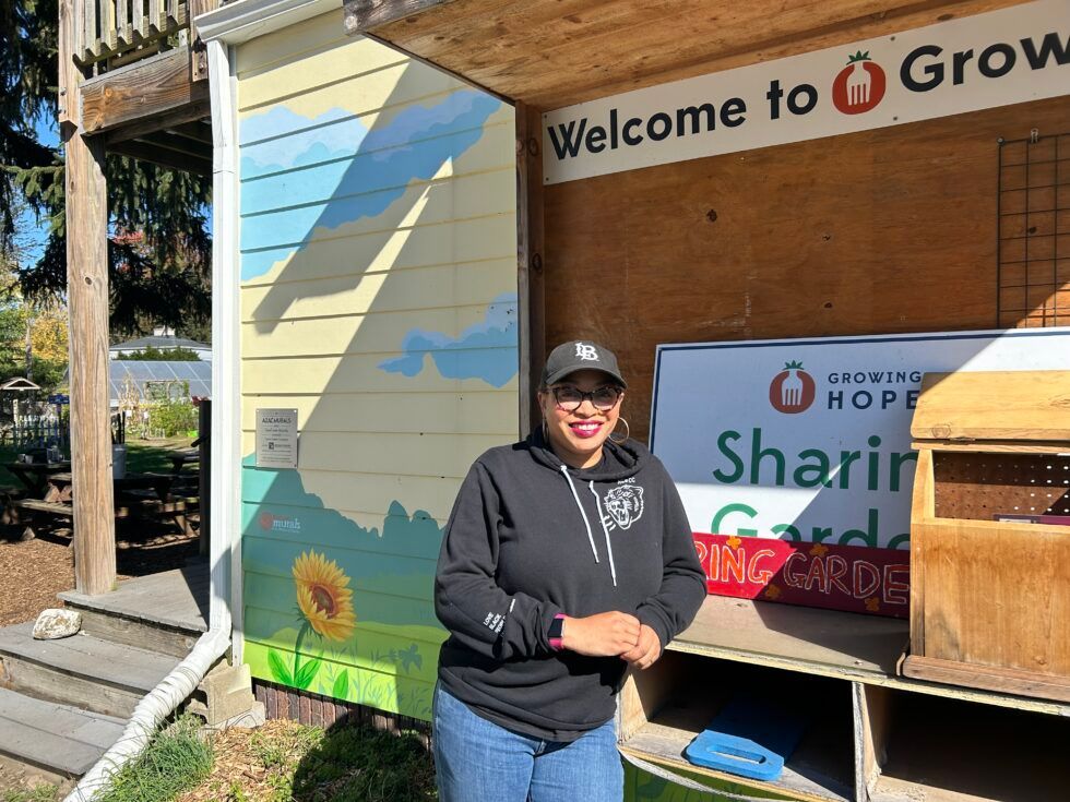 A woman is standing in front of a building with a sign that says welcome to grow.