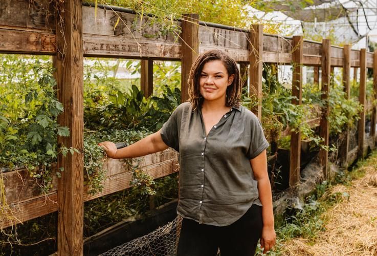 A woman is standing next to a wooden fence in a garden.