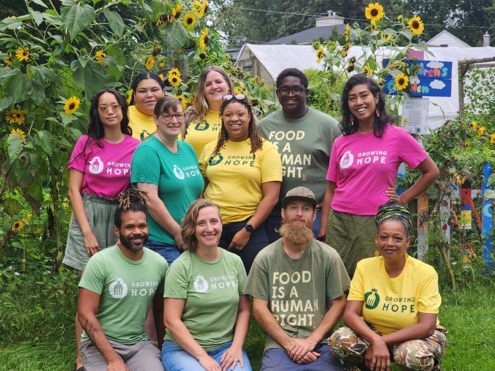 A group of people are posing for a picture in front of sunflowers.