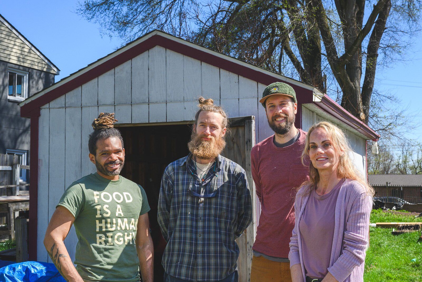 A group of people are standing in front of a shed.