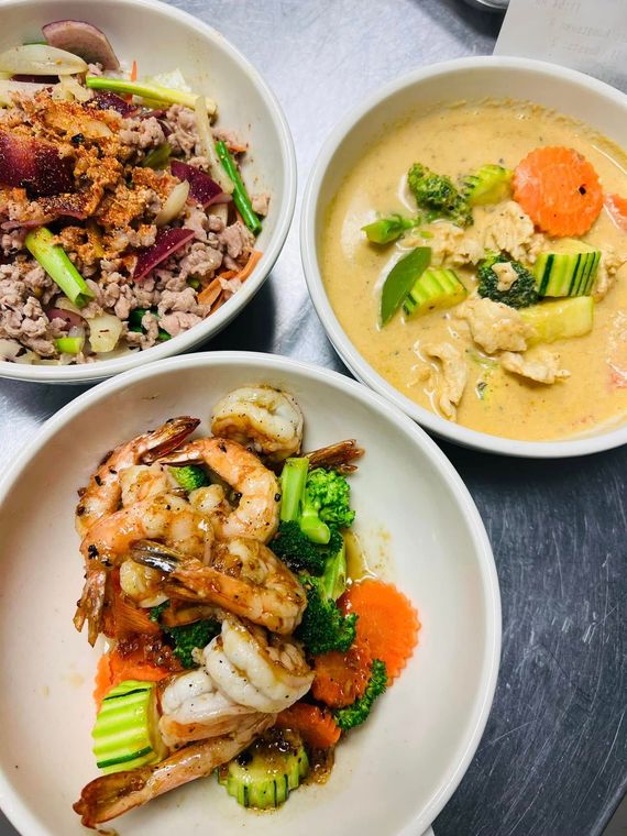 Three bowls of food are sitting on a table.