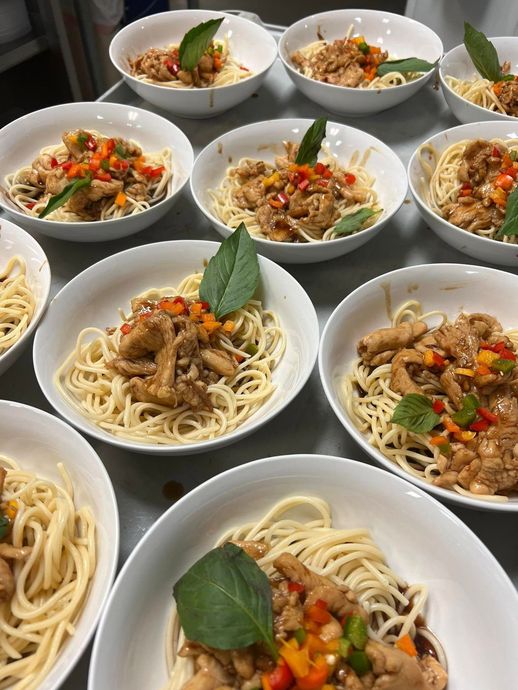 A bunch of bowls of spaghetti with meat and vegetables on a table.