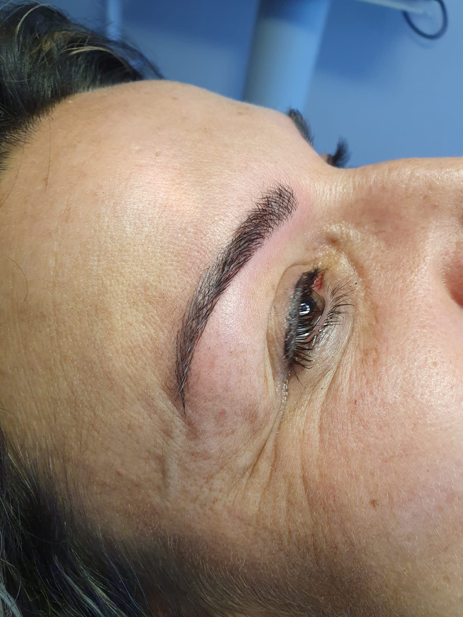 Un primo piano del volto di una donna con un tatuaggio sulle sopracciglia.