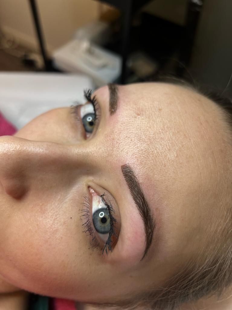 Un primo piano del volto di una donna con un tatuaggio sulle sopracciglia.