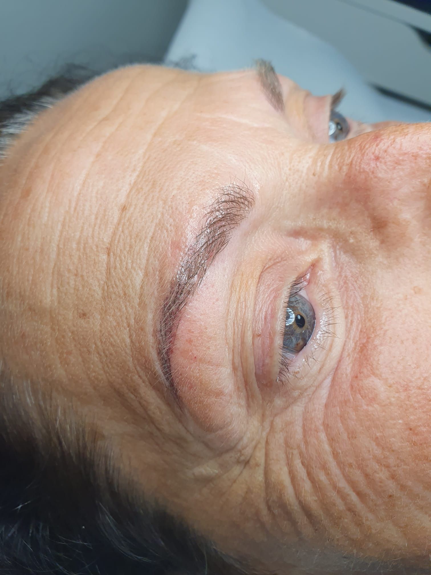 Un primo piano del volto di una donna con un tatuaggio sulle sopracciglia.