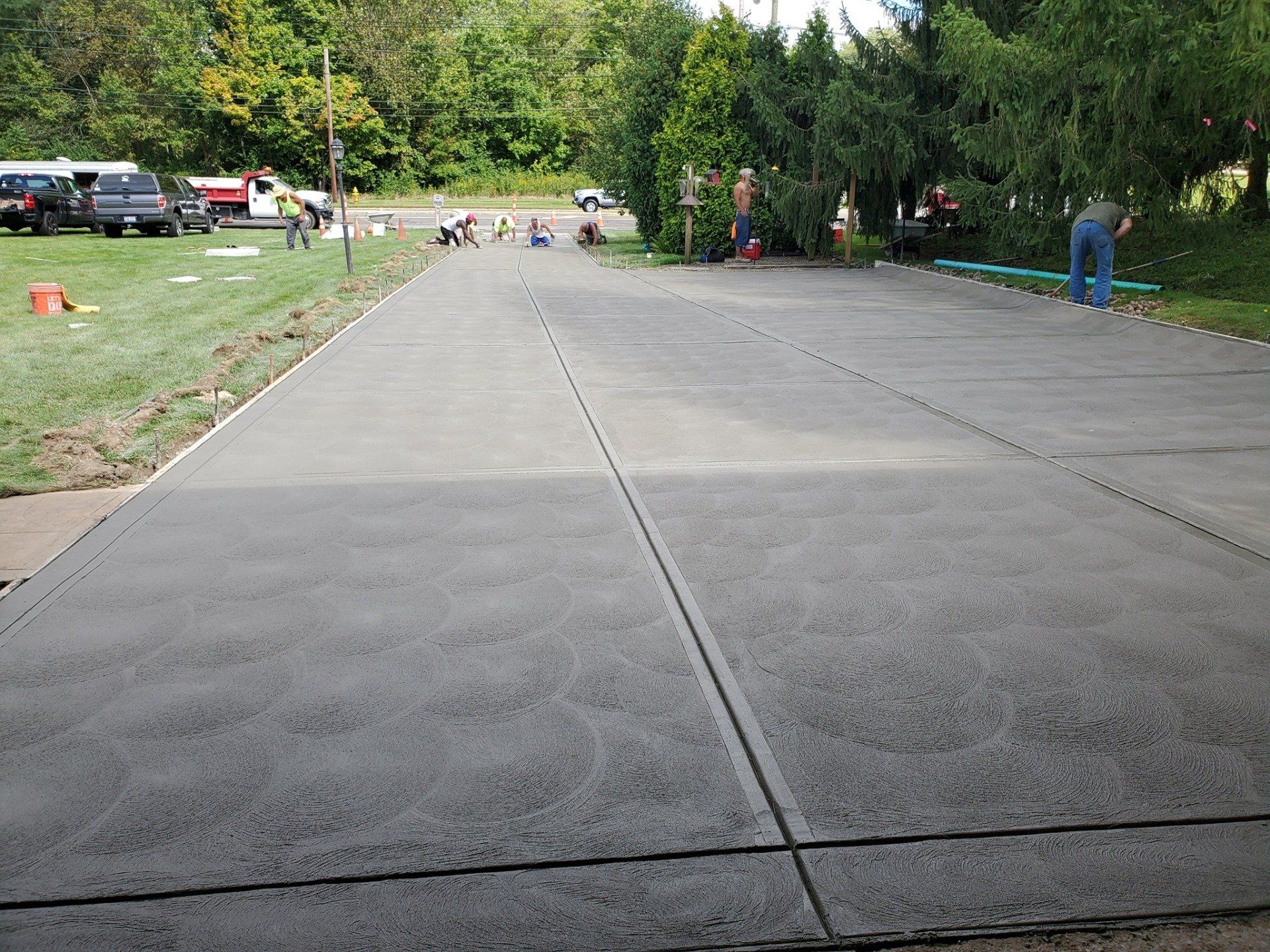 Newly poured concrete driveway with workers in background.