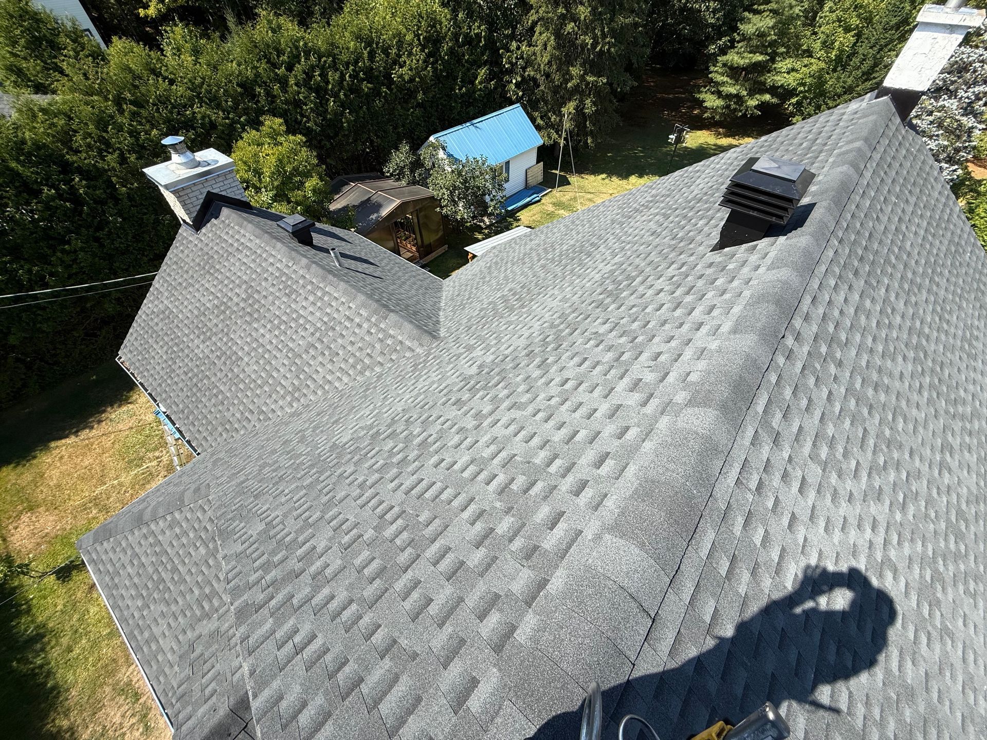 Toit en bardeaux d'asphalte gris sur une maison, vu d'en haut par une journée ensoleillée.