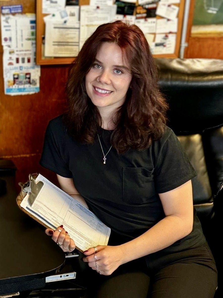 A Woman Is Sitting at A Table Holding a Clipboard and Smiling - San Rafael, CA - Japan Auto Repair
