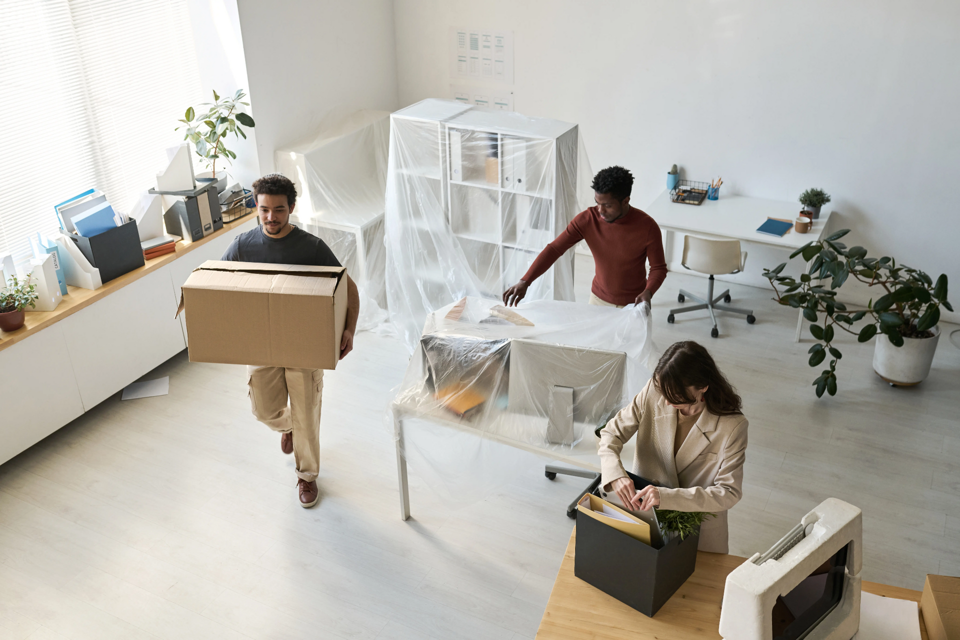Employees packing boxes and preparing office furniture during a commercial office relocation and move.