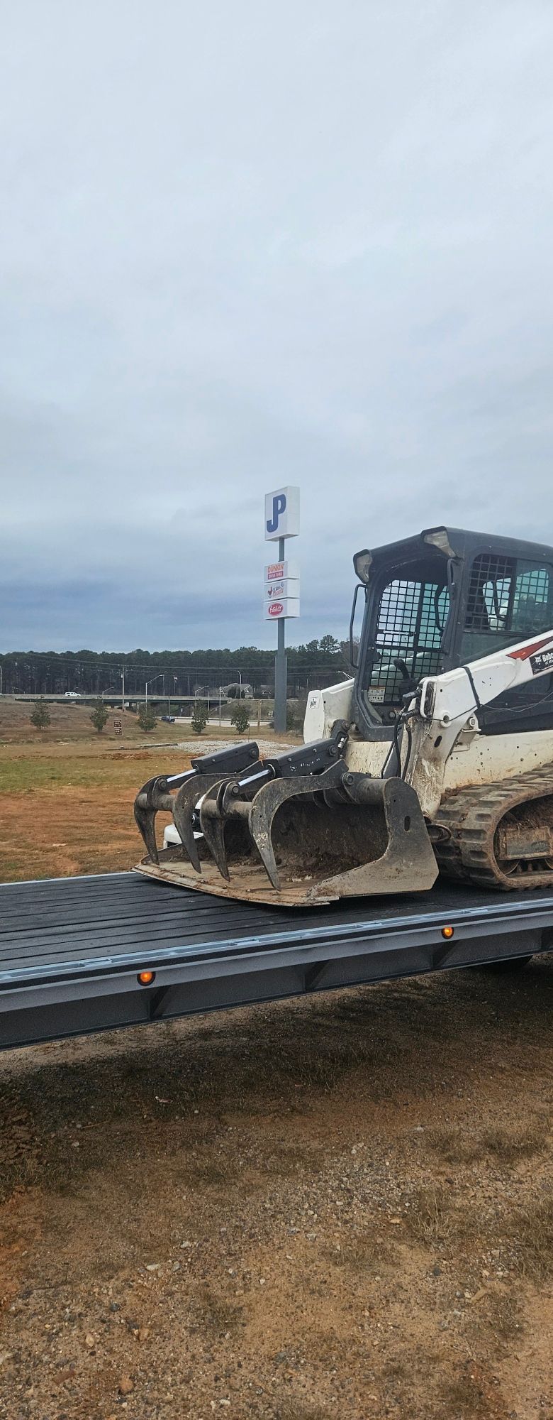 A cart holding numerous orange chainsaws with safety guards, in a cluttered workshop setting.