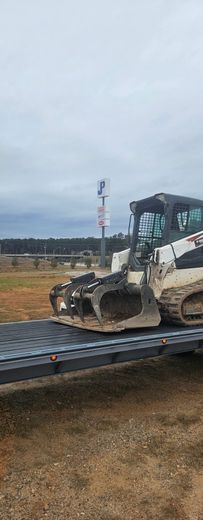 A cart holding numerous orange chainsaws with safety guards, in a cluttered workshop setting.
