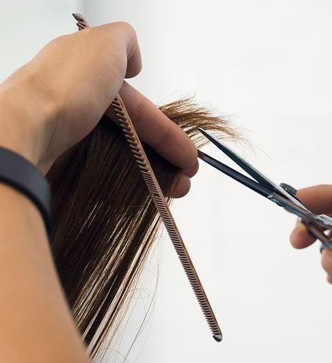 A Woman Is Getting Her Hair Cut By A Hairdresser — Elements Hair Artists In Belmont, NSW