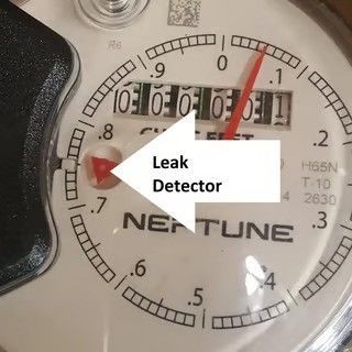 Close-up of a Neptune water meter with red leak detector indicator and numbered dial. Close-up of a Neptune water meter with red leak detector indicator and numbered dial.