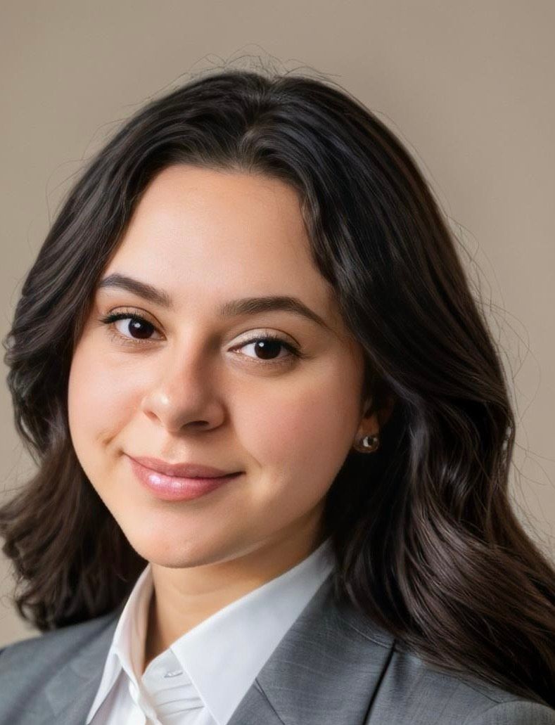A woman in a suit and white shirt is smiling for the camera